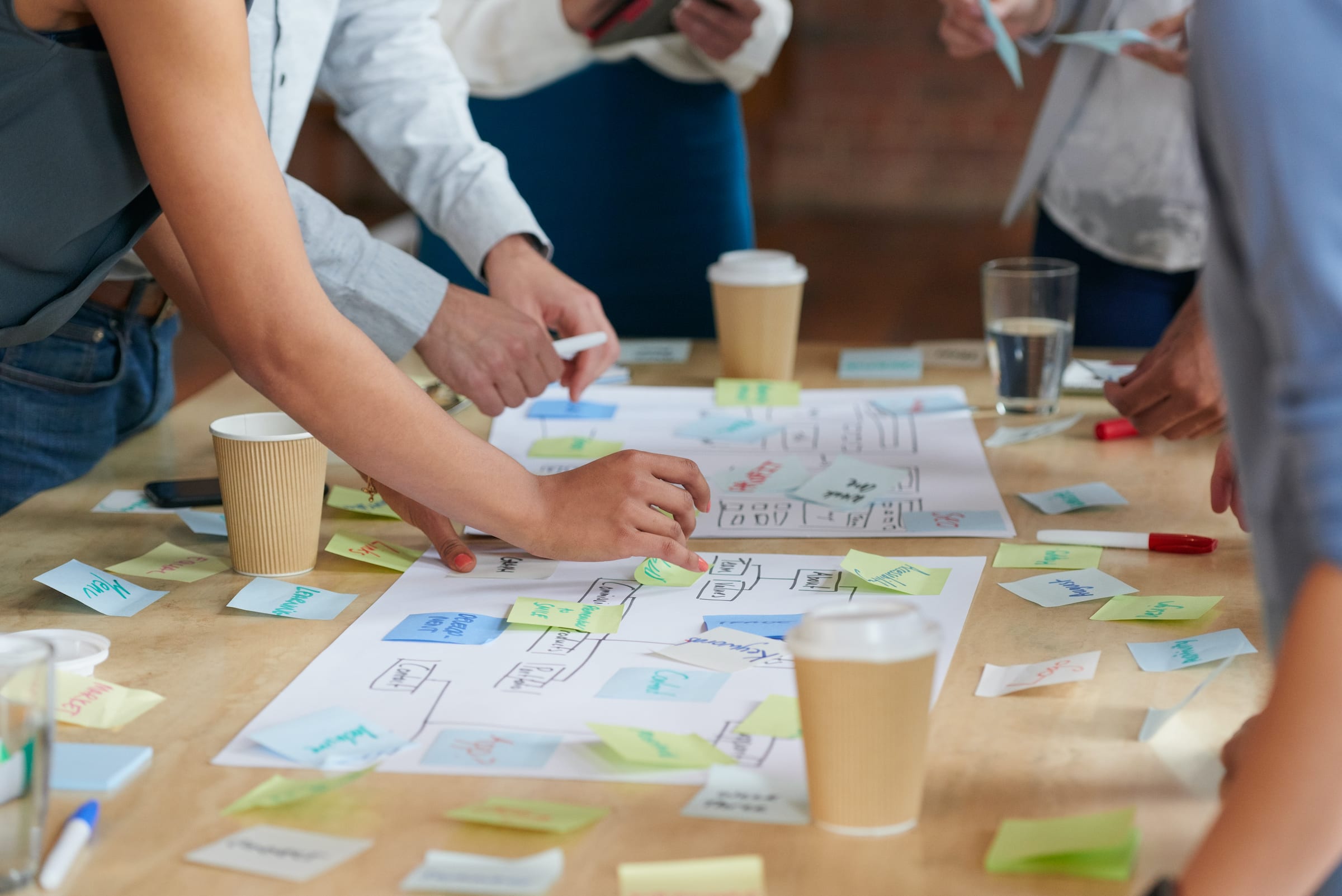 Team standing around table with post-it notes coming up with a design roadmap