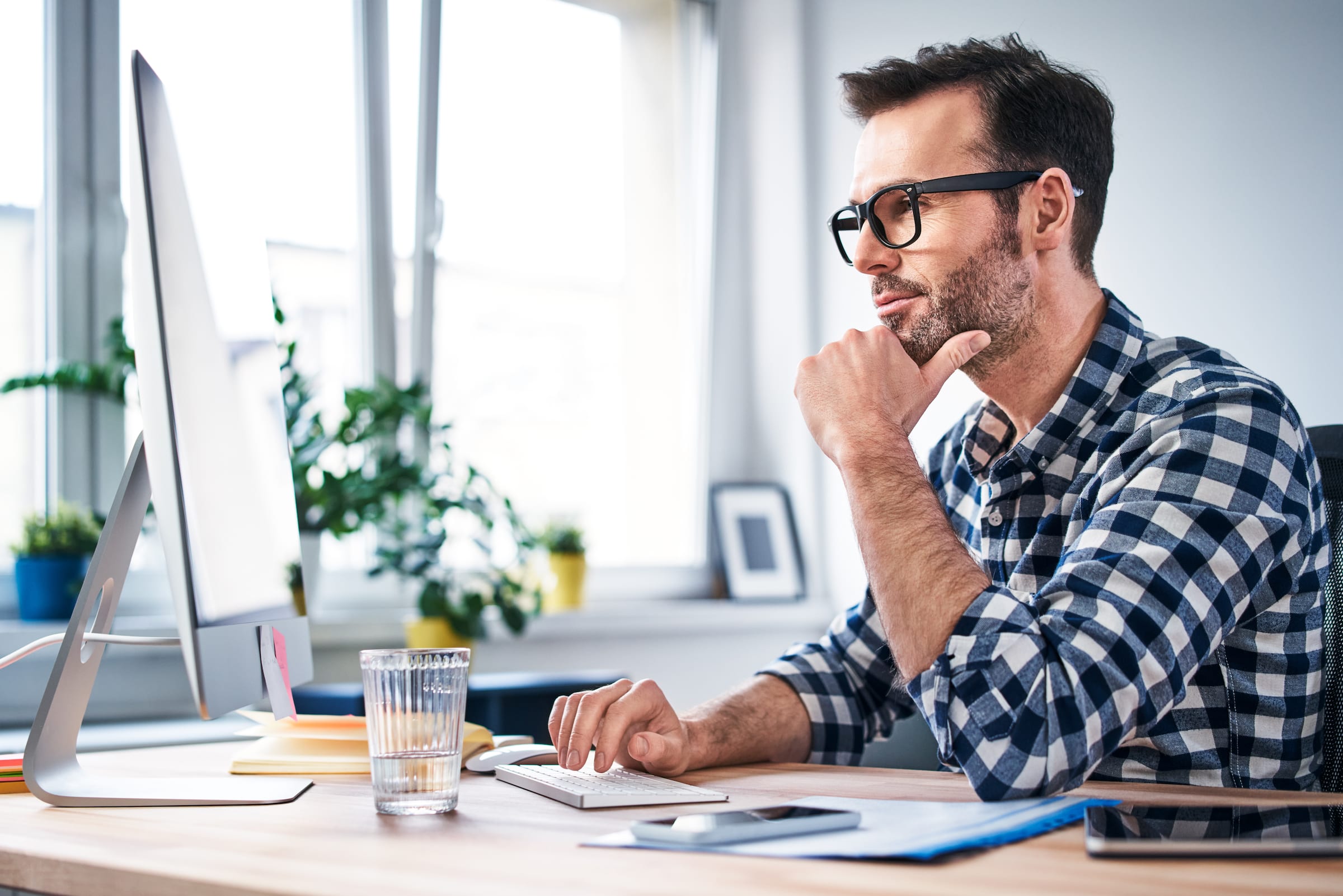 Man sitting at desk with computer thinking to himself