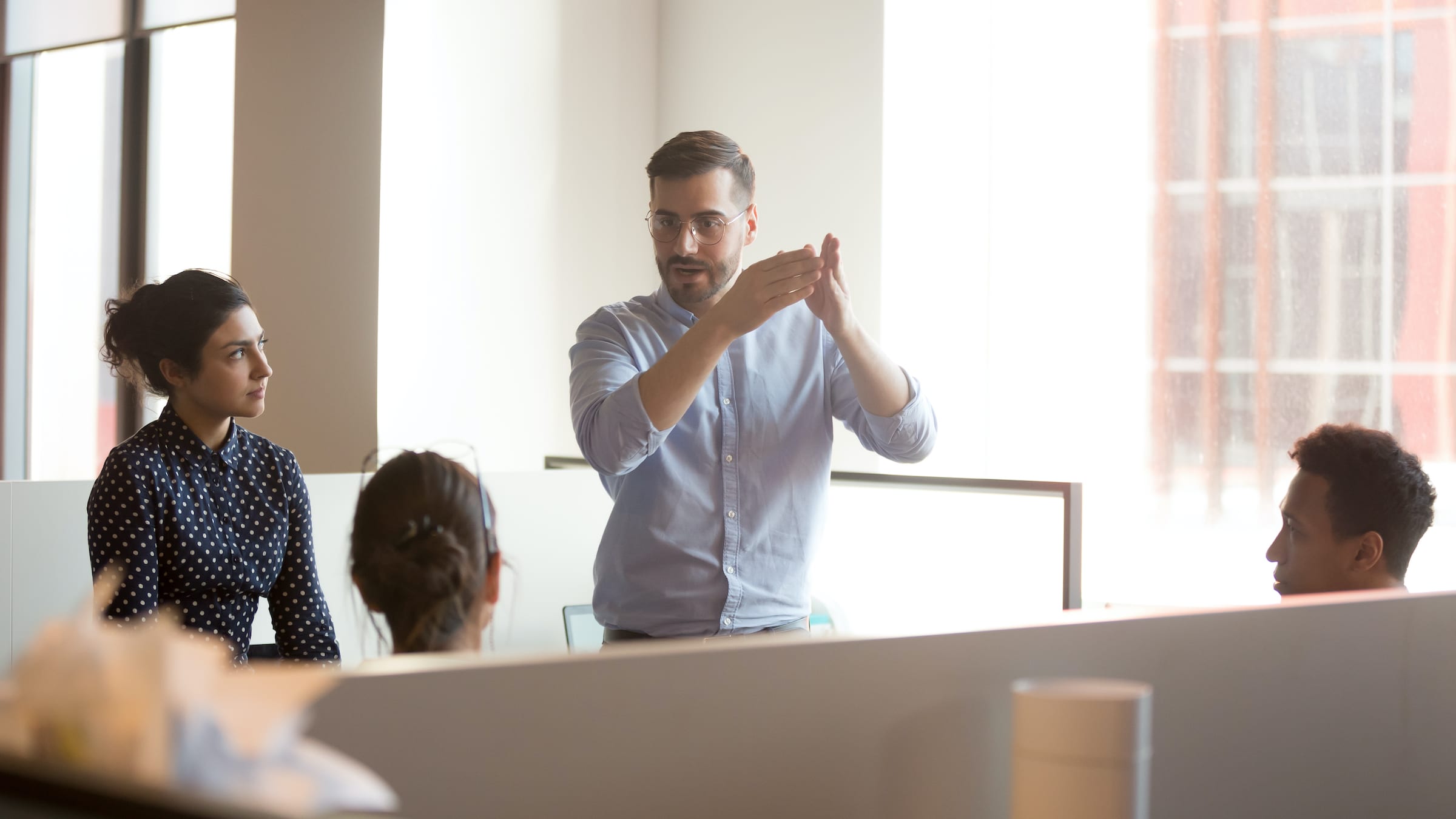 Man in office talking to team discussing the UX paradox