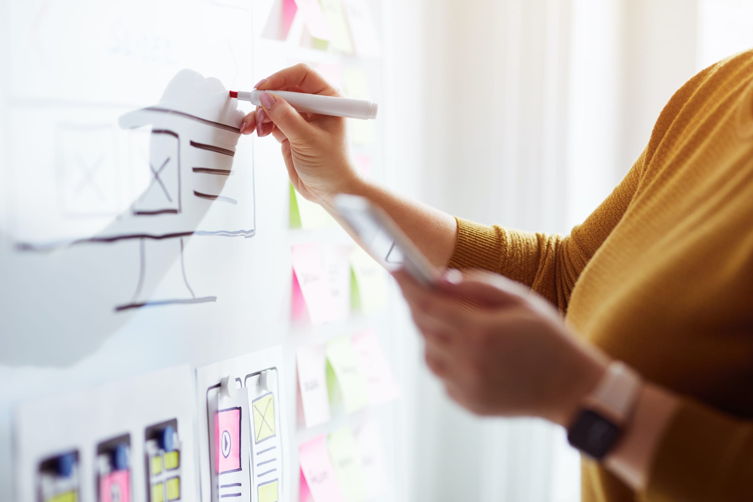 A UX UI designer drawing on a whiteboard