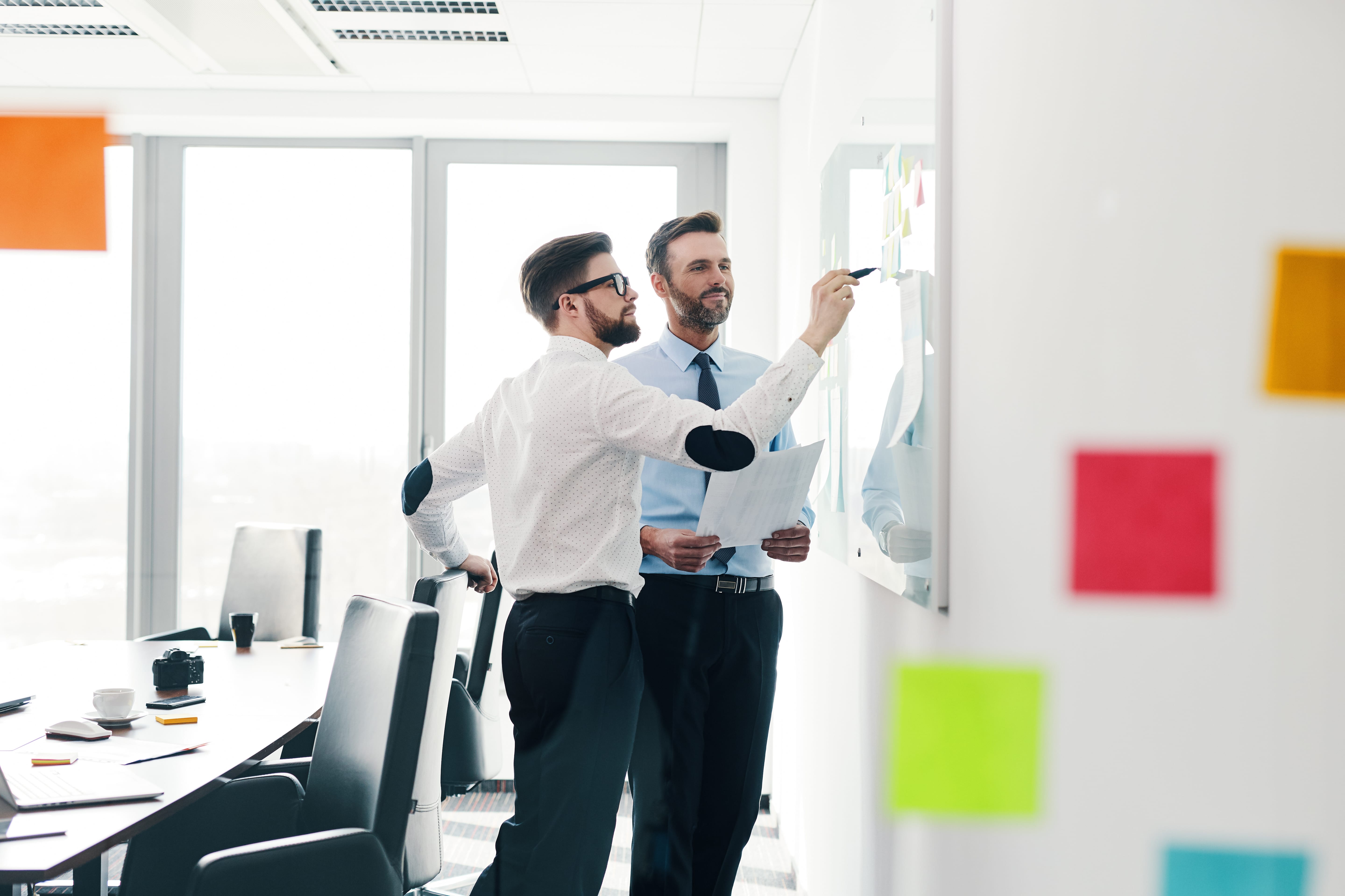 two men working at a whiteboard on a project